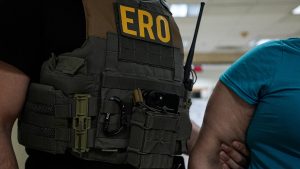 ERO agent holding an illegal immigrant's arm